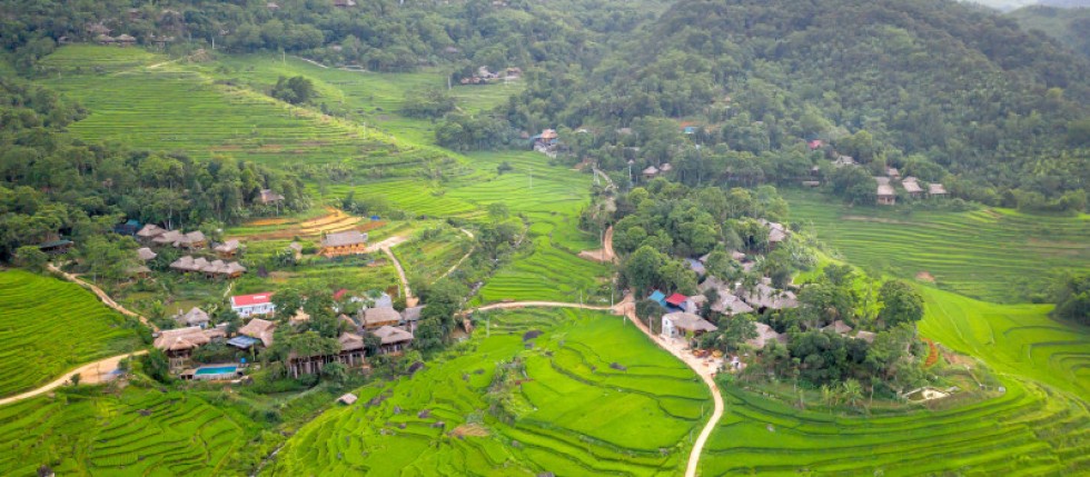 Imagem aérea de terrenos urbanos e agrícolas com aldeia e muito verde à volta.