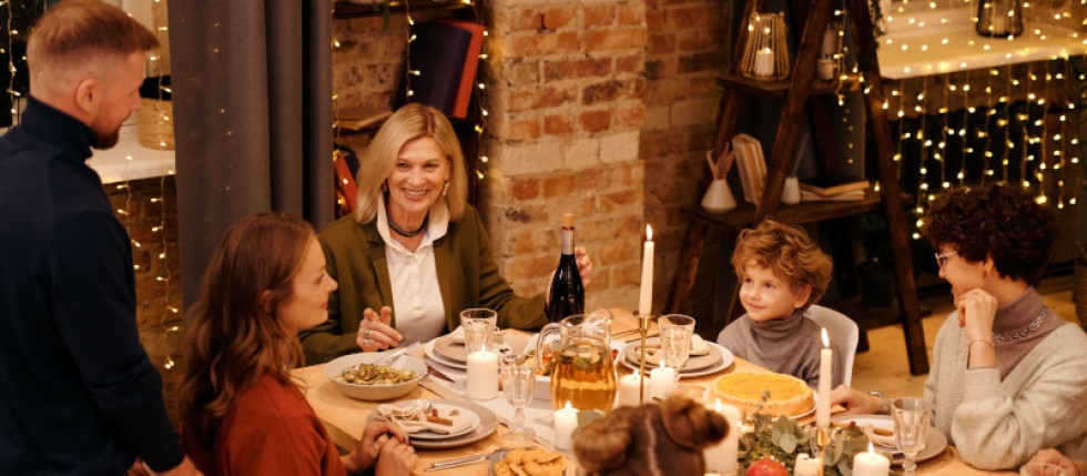 Família sentada à mesa a jantar depois de organizar a ceia de Natal