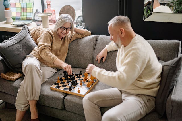mulher e homem idosos jogam xadrez no sofá
