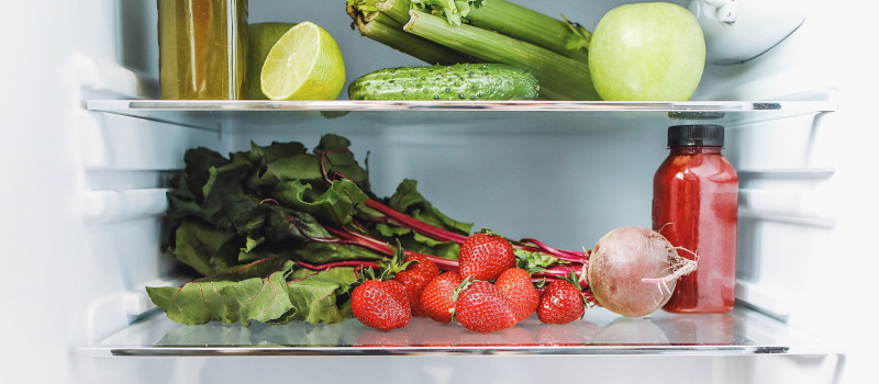 Legumes verdes e vermelhos dentro de uma geladeira para mostrar como limpar frigorifico.