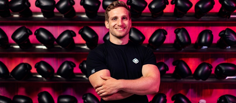 personal trainer em sala de ginásio com estante de luvas de boxe atrás