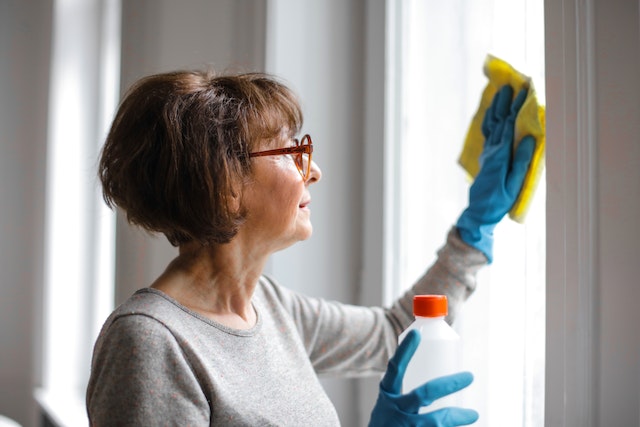 mulher usa mistura e pano para limpar vidros de janela