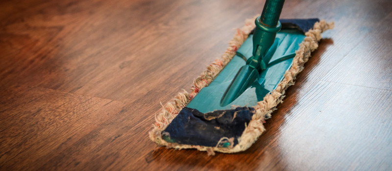 Cabo de esfregona mostra como limpar chão de madeira castanha.