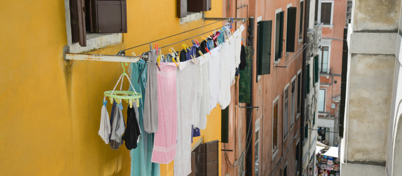 Um estendal à janela num prédio amarelo é uma das soluções para estender roupa em apartamento.